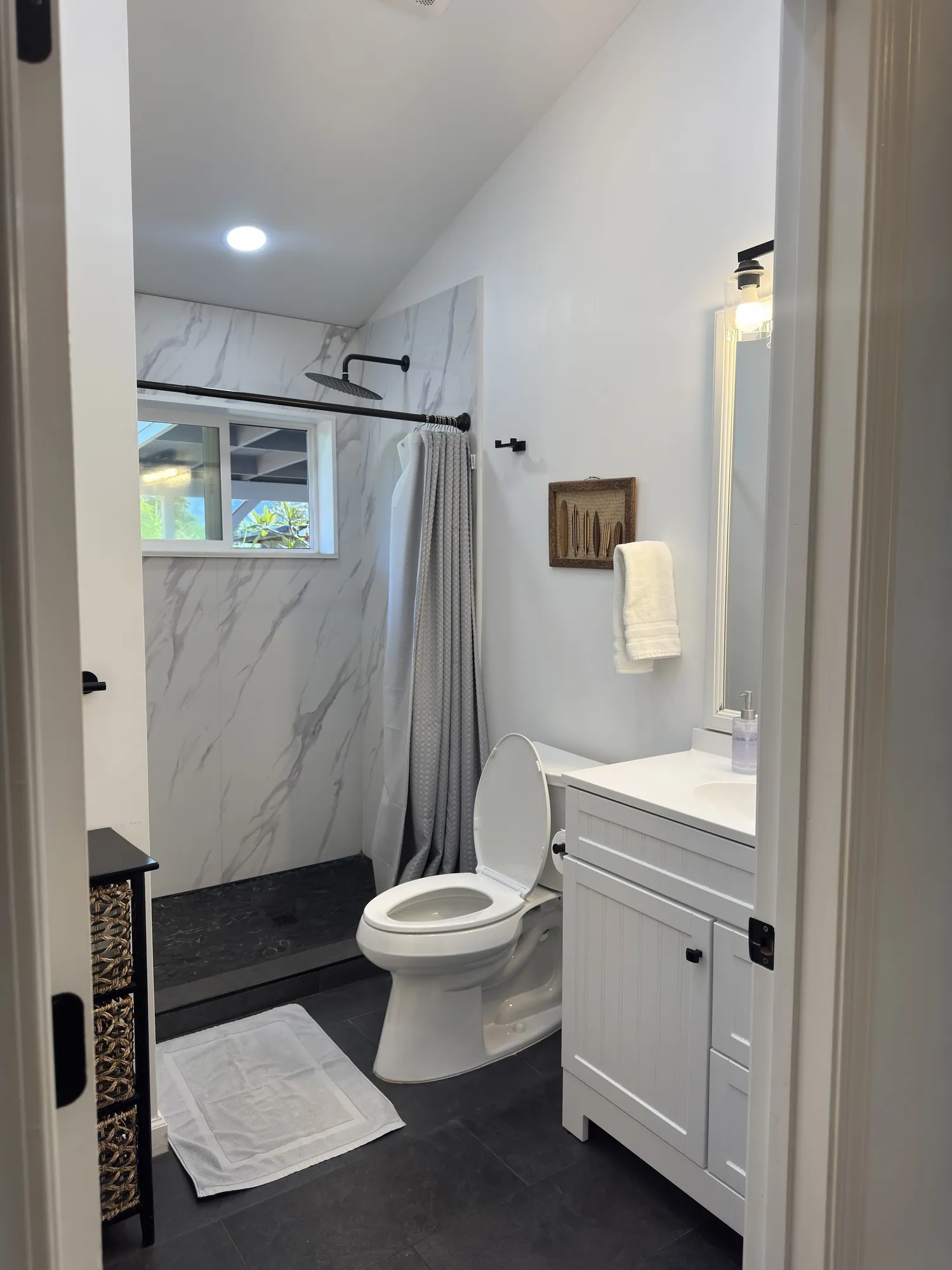 The second bathroom: marble-tiled shower with a window, vanity and towel bar